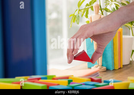 Composite image of cropped image of person arranging blocks Stock Photo