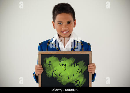 Graphic image of letters against schoolboy holding blank writing slate against white background Stock Photo