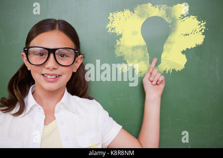 Cute pupil pointing against digital composite image of light bulb on black spray paint Stock Photo