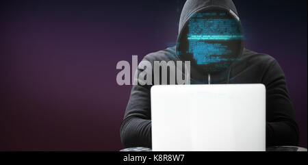 Hacker wearing black hood while using laptop on table against pink and purple background Stock Photo