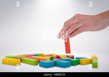 Cropped hand arranging blocks against grey background Stock Photo