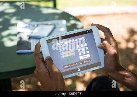 Internet banking text with log in page on phone against man using digital tablet at outdoor restaurant Stock Photo