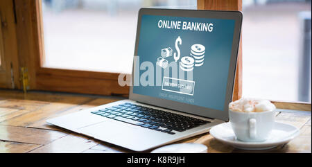 Online banking text on blue display against laptop by coffee cup on table in cafe Stock Photo