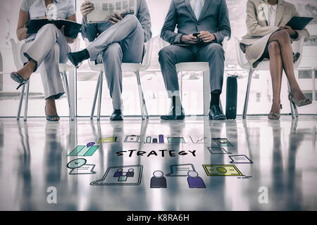 Strategy text surrounded by various icons against group of well dressed business people waiting Stock Photo