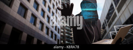 Hacker holding laptop while gesturing against high angle view of crowded buildings in city Stock Photo