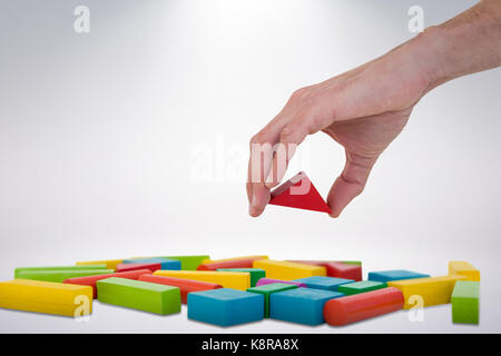Cropped image of person arranging blocks against grey background Stock Photo
