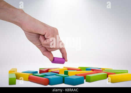 Cropped hand arranging plastic blocks against grey background Stock Photo