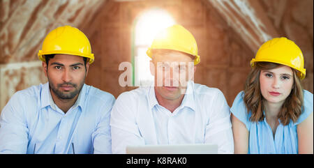 Portrait of architects wearing hardhats while sitting at table against room in house under construction Stock Photo
