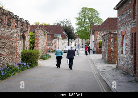 People walk down a road and past red brick buildings in Chichester, West Sussex, England. Stock Photo