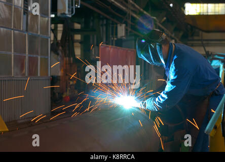 Welder performs welding large diameter pipe inside plant Stock Photo