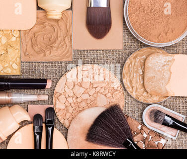 Makeup products to create the perfect complexion. Foundation, compact, loose and shimmer golden powder, crushed bronzing powder, brushes and sponges Stock Photo
