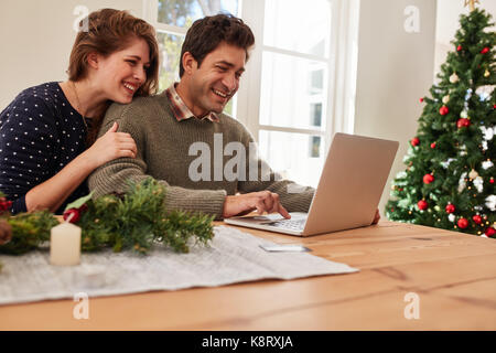 Young man and woman buying christmas and new year gifts from internet. Couple doing online shopping for christmas.