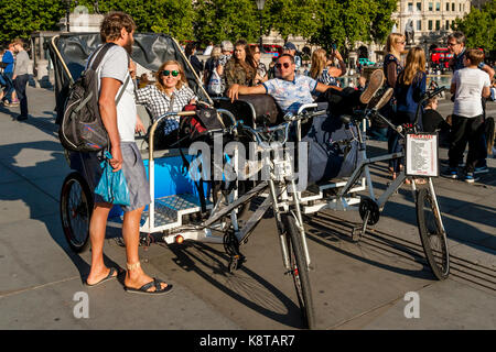 Pedicab Drivers Relaxing In The Sunshine Waiting For A Fare, Trafalgar Square, London, UK Stock Photo