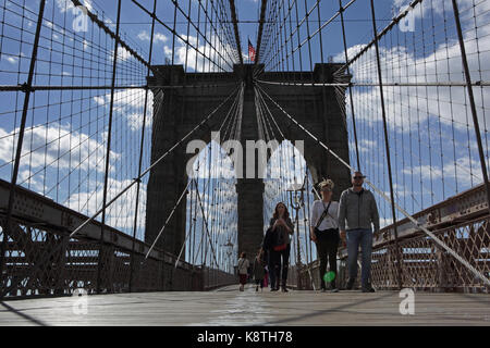 New York, NY, USA - May 3, 2017: Worms eye view of people walking to Manhattan across the Brooklyn Bridge on a sunny day Stock Photo