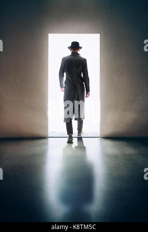 Man silhouette walking away in the light of opening door in dark room. escape concept Stock Photo