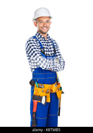 Happy smiling construction worker in uniform and tool belt with crossed arms isolated on white background Stock Photo