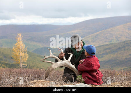 tsaatan boy and his grandfather dressed in a traditional deels resting in nature Stock Photo