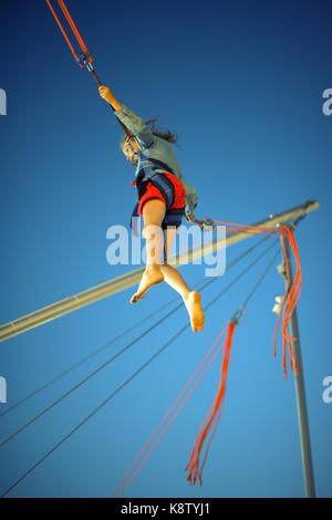 Little girl on bungee trampoline with cords Stock Photo