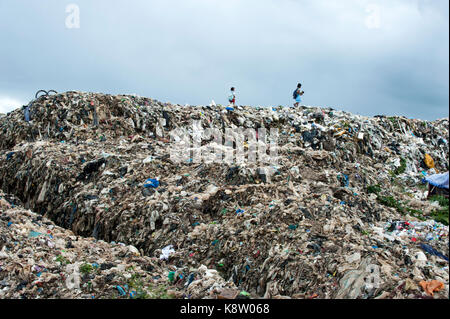 Burmese migrant children walk home after school through the rubbish dump site in the outskirts of the border town of Mae Sot, Thailand August 16 2017. Stock Photo