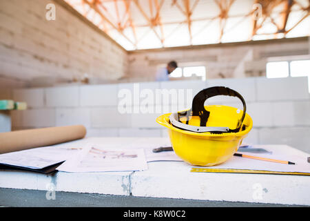 Helmet and blueprints on construction site. Stock Photo