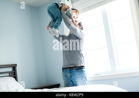 Happy young father holding cute boy standing near big window. Stock Photo