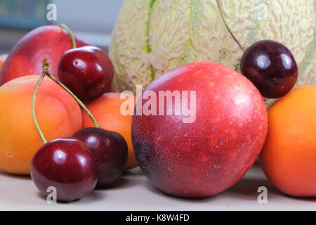 Heap of summer fruits on a table : apricots, nectarines, cherries and melon Stock Photo