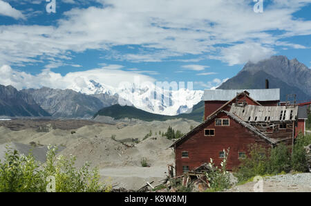The decaying buildings of the Kennicott mine sit at the base of snowy mountains. Stock Photo