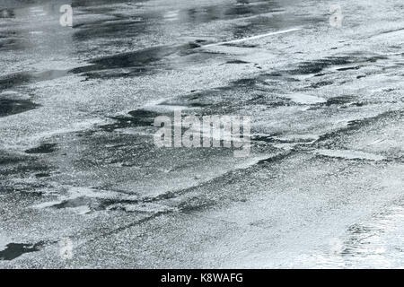 wet bumpy asphalt road with water puddles after rain Stock Photo