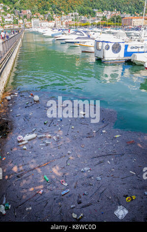 Floating rubbish and trash along side expensive yachts at the Como marina. Stock Photo