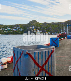 Fish storage boxes on jetty with Signal Hill in the background, St John's, Newfoundland, Canada Stock Photo