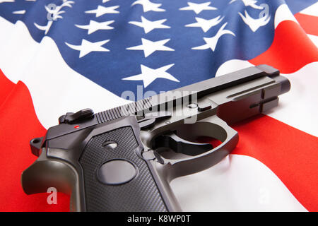 Handgun lying on satin USA flag - close up studio shoot Stock Photo