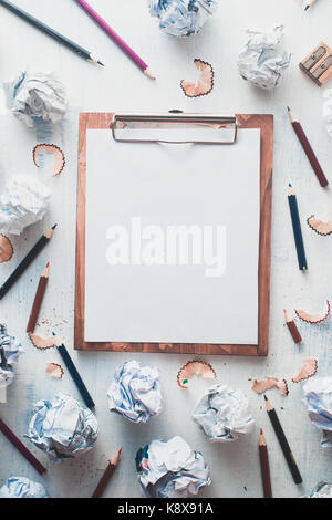 Wooden tablet with blank pages, crumpled paper balls and pencils on a white wooden background, creative writing concept. Minimalist writer workplace Stock Photo