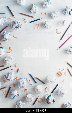 Circle copy space with a frame of crumpled paper balls and pencils on a white wooden background, creative writing concept.