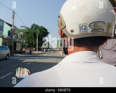 Hue, Vietnam - September 13 2017: Close up of unidentified man with a white helmet, riding a motorcycle in the street in the city of Hue, Vietnam Stock Photo