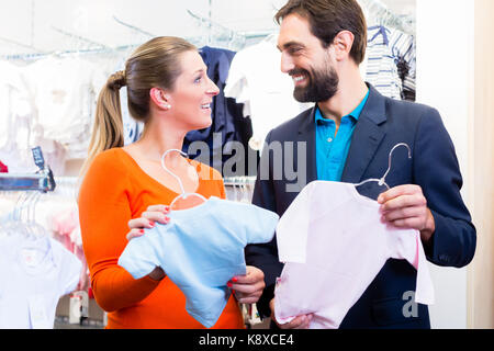 Woman and man expecting twins buying baby clothes Stock Photo