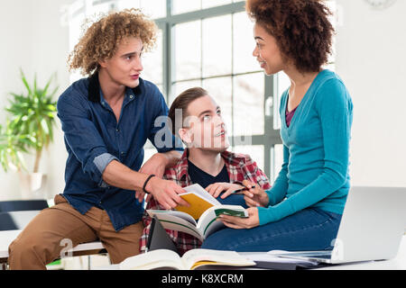 Three students comparing information from two different textbook Stock Photo