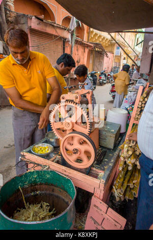 Jaipur, India - September 20, 2017: Unidentified man working with a machine to extract refreshing juice from sugar cane, in an alley in Jaipur Stock Photo