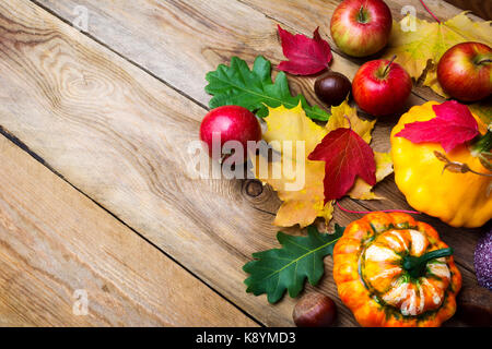 Ripe red apples, decorative pumpkin, chestnut and yellow gourd with colorful fall leaves on the rustic wooden table, copy space. Thanksgiving or fall  Stock Photo