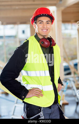 Carpenter Standing With Hands On Hips At Construction Site Stock Photo