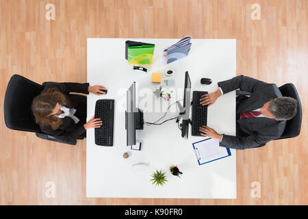 High Angle View Of Two Businesspeople Working On Computers In Office Stock Photo