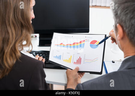 Close-up Of Two Businesspeople Discussing Graph In Office Stock Photo