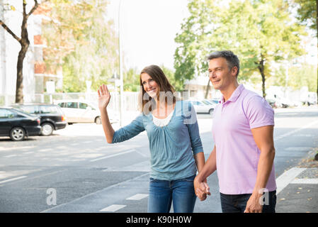 Portrait Of Happy Couple Hailing For Taxi Stock Photo