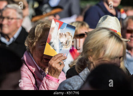 Giessen, Germany. 21st September, 2017. A woman holds up a broshure featuring Angela Merkel to shield her eyes from the sun, at a Hesse CDU election campaign event in Giessen, Germany, 21 September 2017. Credit: Frank Rumpenhorst/dpa/Alamy Live News Stock Photo