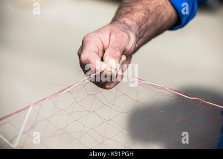 Fisherman in Adriatic sea prepares net for fishing with their hands. Stock Photo