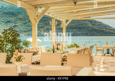 Fragment of the old cafe on the water is a favorite tourist place with a delicious local cuisine and a beautiful view of the Bay of Kotor, Perast, Mon Stock Photo