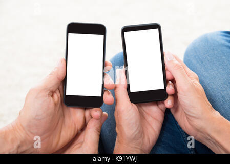 Close-up Of Two People Hands Holding Blank Display Mobile Phones Stock Photo