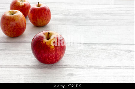 Closeup of four whole red apples on grey wooden background with copy space. Backlit. Stock Photo