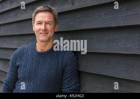 Portrait shot of an attractive, successful and happy smiling middle aged man male outside wearing a blue sweater Stock Photo
