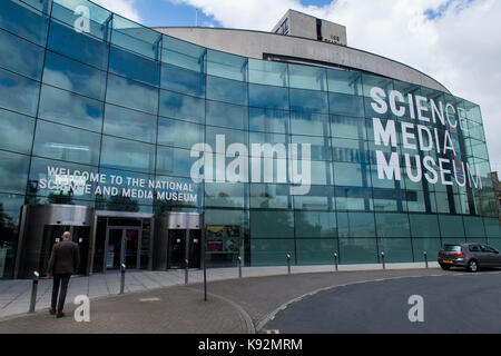 Exterior view of The Science and Media Museum (Bradford, West Yorkshire, England, UK) with impressive, curved, glazed facade - man walks to entrance. Stock Photo