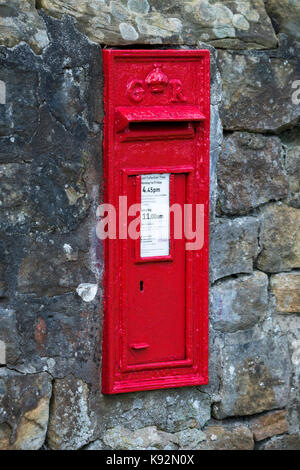 Close-up of traditional, bright red, King George V, Royal Mail post box set into a stone wall - Rudding Lane, Harrogate, North Yorkshire, England, UK. Stock Photo
